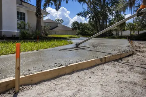 Wet concrete being poured and floated inside form boards on a residential driveway