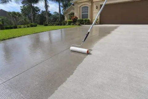 Concrete driveway half-coated with fresh clear sealer showing a satin sheen