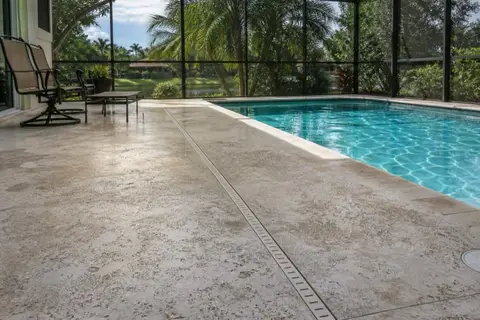 Screened Florida pool deck in light textured concrete with water reflections