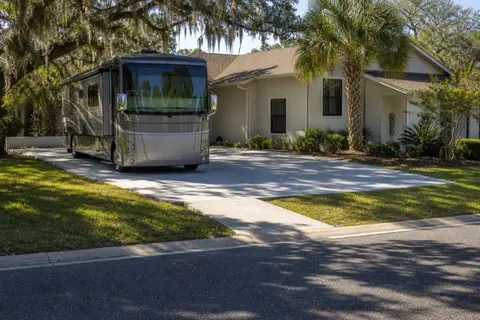 Wide concrete parking pad beside a Florida home with a motorhome parked on it